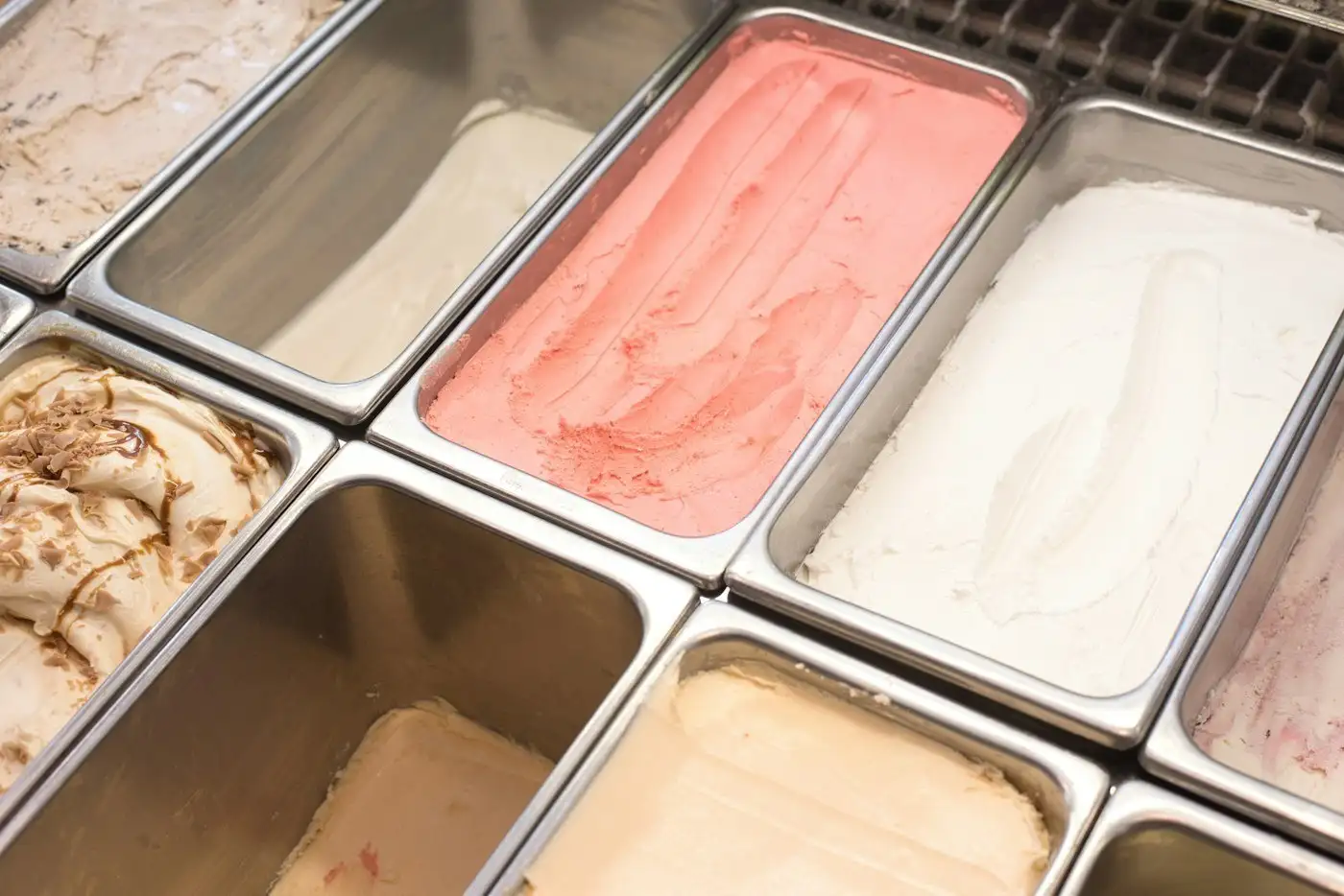 Steel pans of strawberry, vanilla and chocolate swirl ice cream in a dipping case